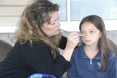 Karen Haines starts painting on a rainbow whale during the opening day of the second season of the farmers market.