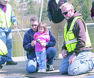 Brian Anderson and his daughter Emily fish with the help of volunteer Phil Pierson in the holding pond during last year's fishing derby off of the Lake Wilderness dock where they are guaranteed a fish.