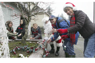 Helping decorate one of the 150-plus homes that will be part of a holiday lights show and food drive tomorrow night at Lake Wilderness Country Club are (from left) Erin Asch and children James and Andrew