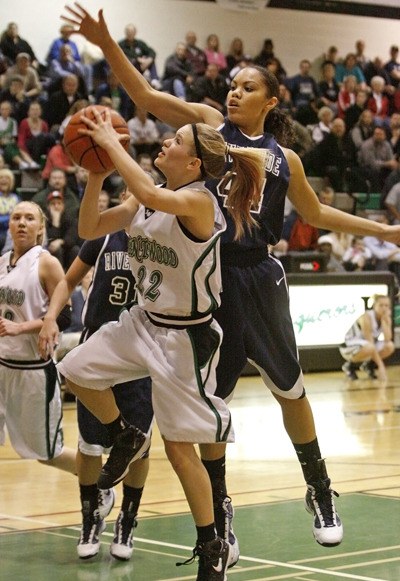 Auburn Riverside's Kathleen Cooper blocks and fouls Kentwood's Maddison Rankin as she drives the lane Tuesday