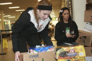 Two Kentwood students work on weighing the amount of food as part of the school's Munch Madness Food Drive.