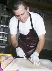 Nelson Amador cuts up chicken breasts for the Corner of Love Nica Dinners fundraiser.