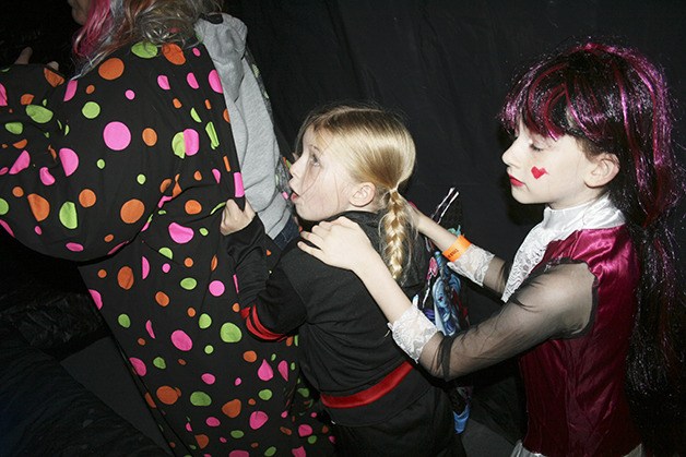 Laura Morceau (left) leads frightened costumed kids Angelena Sloan (middle) and Isabelle Morceau (right) through a haunted house Oct. 31.