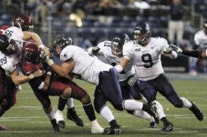 Kentwood product Ryan Conwell (No. 99 at left) pulls down a Central Washington ballcarrier while former Kentlake star Shane Simmons (No. 9 far right) swoops in to help finish the play. Simmons
