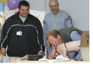 Frank Whylie kisses a piglet while fellow Shadow Lake Elementary School teachers Scott Michelle (left) and Clark Kostohris wait their turn.
