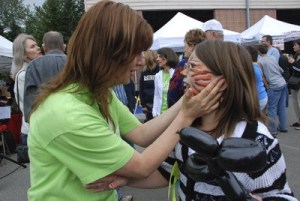 Kim Emmons checks out face painting work on her granddaughter Alex’s face at the opening day of the Maple Valley Farmer’s Market last year.