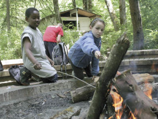 Roasting hot dogs on an open flame is a lunchtime treat for Brelin Denton and Lizzy Platin.