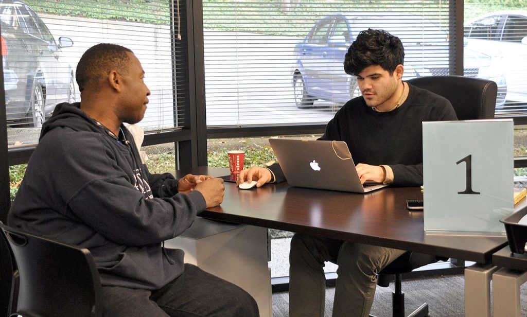 Uber expert Oscar Romero, right, helps Gary Tarver, of Tacoma, sign up to become an Uber driver-partner at the new Greenlight Hub in Tukwila. The hub, which moved from Pioneer Square in Seattle, provides Uber driver-partners with in-person support and assistance. HEIDI SANDERS/Tukwila Reporter