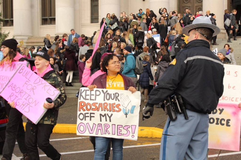 A dozen or so counter protesters included Aquila Krause, shown here speaking with a Washington State Patrol officer near the Temple of Justice at the Capitol. Photo by Taylor McAvoy, WNPA Olympia News Bureau