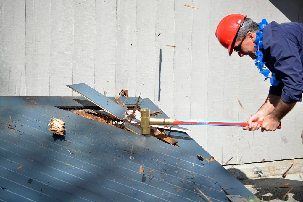 Deputy Major, Dana Parnello, slams a giant hammer into the old beach house door. Photo by Kayse Angel