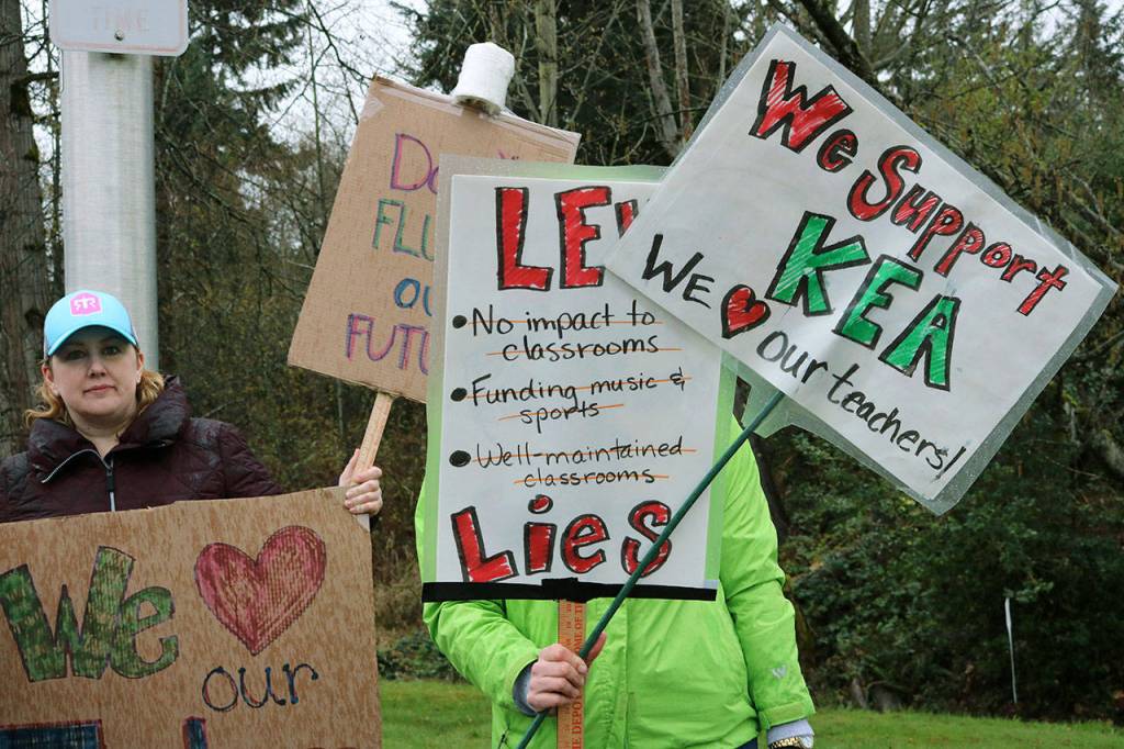 Local moms Dana Rosenberg, left, and Erin Leithead, right, wave their homemade signs at passing traffic on 256th Street in Kent outside of the KSD headquarters, drawing honks and cheers from drivers and passengers. Megan Saunders photo, for the Reporter