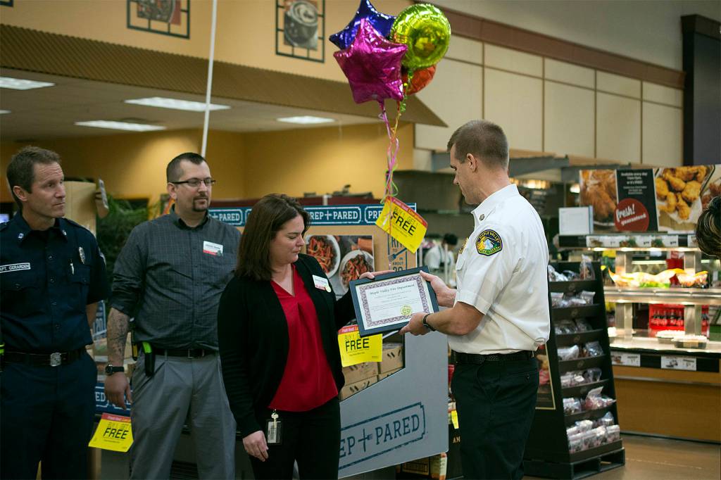 Fire Chief Aaron Tyerman hands the Maple Valley Fred Meyer store manager a framed certificate to thank the Fred Meyer employees for their assistance during an incident at their store. Photo by Kayse Angel