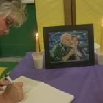Mark Klaas, Kent Reporter                                Carrie Lantz signs a memorial book before the start of a candlelight vigil.