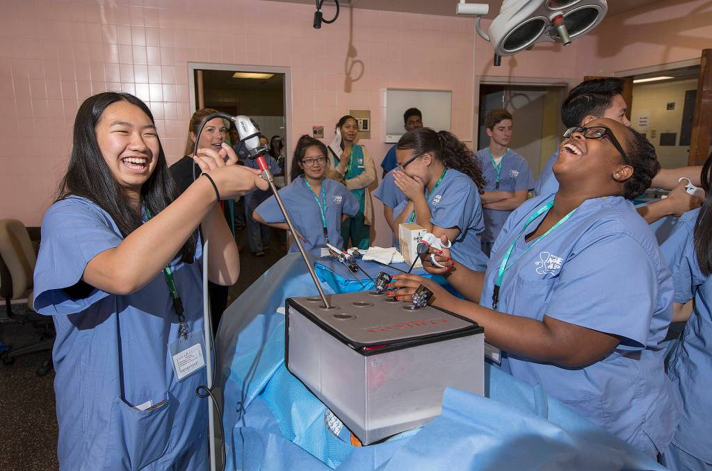 Tiffany Nguyen, 17, left, of Kent, laughs with Tiffany Jinks, 16, of Tacoma, as she attempts to grab candy with an alligator clamp while learning about laparoscopic surgery last week during Nurse Camp at Tacoma General Hospital. Photo by Patrick Hagerty