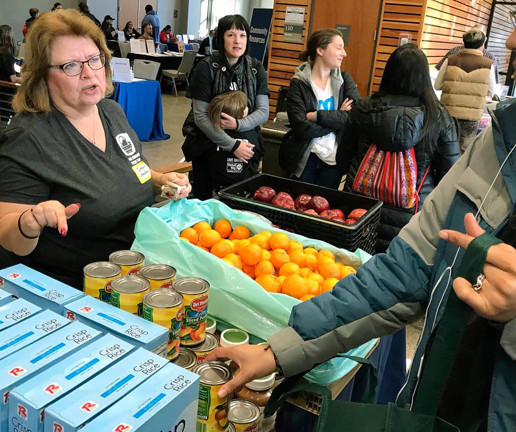 Debbie Christian, executive director of the Auburn Food Bank, distributes fruit and other offerings to families during the United Way of King Countys Family Resource Exchange at Green River College last Saturday.