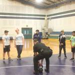 Covington Police Chief Andrew McCurdy shows students how to properly lift a kettle ball weight at the Barbells and Badges summer camp.