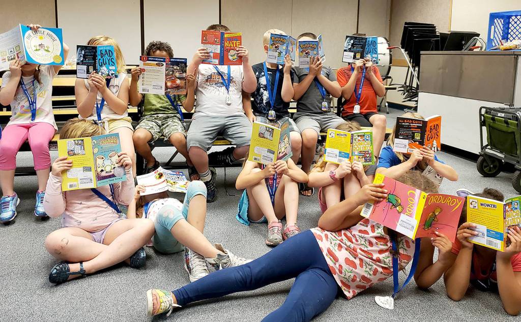 Photo courtesy of the Covington Chamber of Commerce.                                 Children read together at the Covington Library while out of school to earn a brag badge with the Covington Play Unplugged challenge.