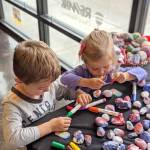 Photo courtesy of the Covington Chamber of Commerce.                                 Two children color rocks to earn a Brag Badge from Covingtons Play Unplugged summer campaign.