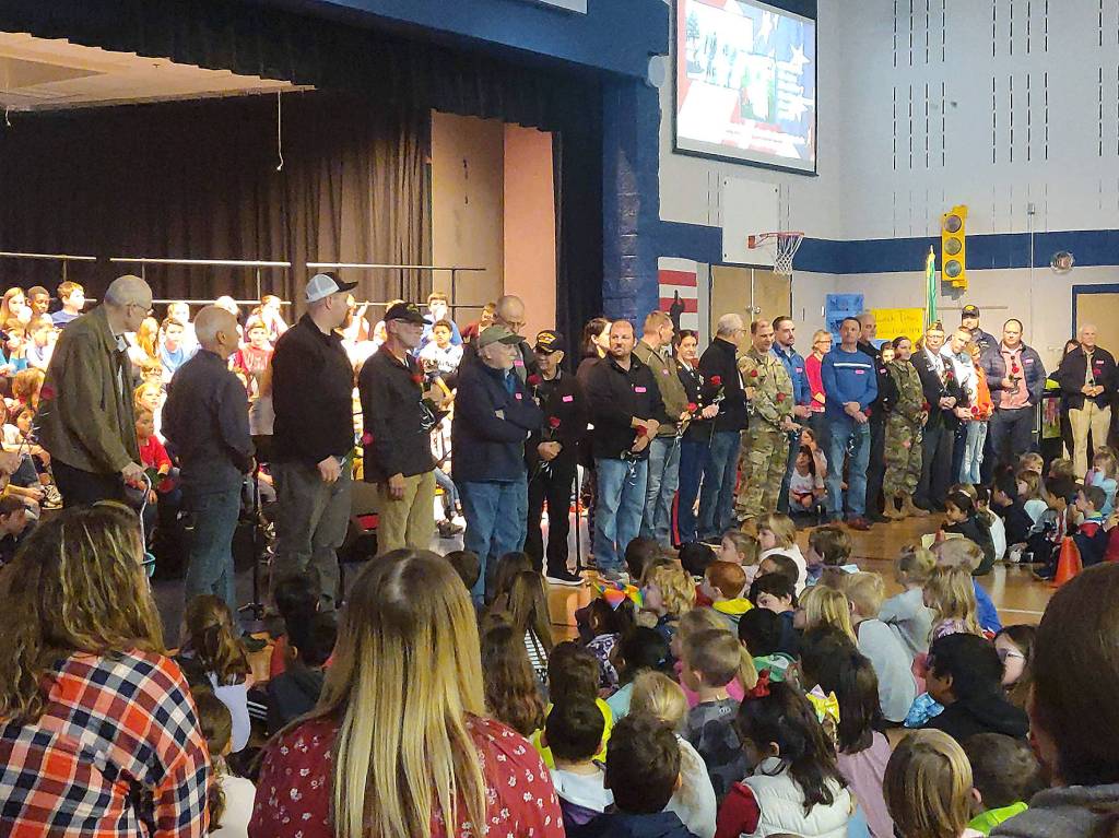 Veterans in the crowd were asked to stand near the stage during a special Veterans Day Assembly. Veterans introduced themselves, said where they served and for what military branch, and were given roses as a thank you for their service by the Glacier Park Elementary School fifth grade class. Photo by Danielle Chastaine.                                 Veterans in the crowd were asked to stand near the stage during a special Veterans Day Assembly. Veterans introduced themselves, said where they served and for what military branch, and were given roses as a thank you for their service by the Glacier Park Elementary School fifth grade class. Photo by Danielle Chastaine.