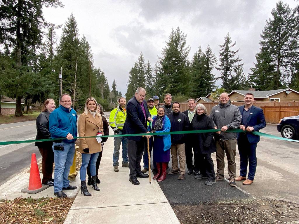 Covington Mayor Jeff Wagner cuts the ribbon on the completed 164th Avenue Southeast Pedestrian Improvement Project on Thursday, Jan. 9, surrounded by city officials.                                Photo courtesy of the City of Covington.