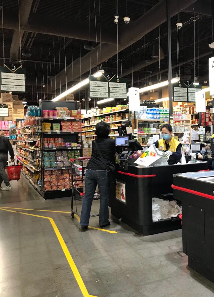 A cashier at H Mart in Bellevue rings up a customer on March 28. Samantha Pak/staff photo