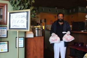 Kabal Gill, owner of East India Grill in Federal Way, wears gloves to hand over take-out orders at his restaurant. File photo