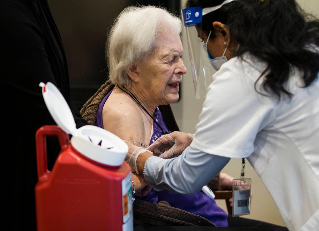 Jackie Hoernor winces as she gets her Pfizer COVID-19 vaccination during a Walgreens Vaccine Clinic at South Pointe on Friday, Feb. 12, 2021, in Everett, Washington. (Sound Publishing file photo)