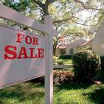 For sale sign hanging in front of house