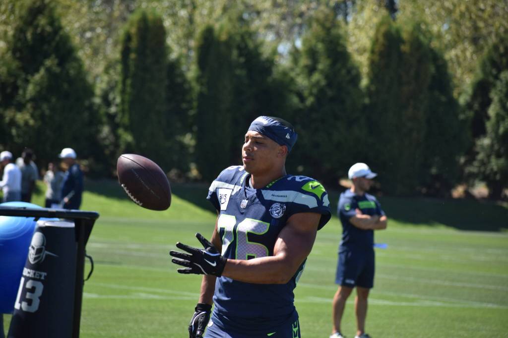 Seattle Seahawks Running Back Zach Charbonnet tosses a ball to a Seahawks coach. Ben Ray / Sound Publishing