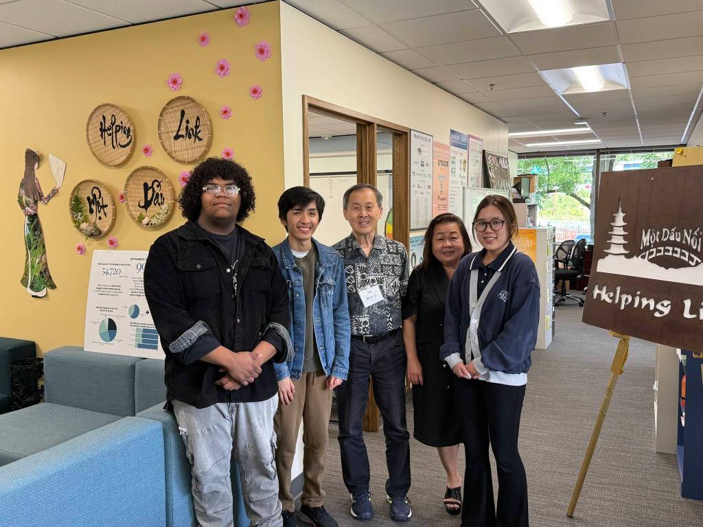 Executive Director Minh-Duc Nguyen (center right) and Ron Choi (center) rely on the work of volunteers to keep Helping Link running. Photo by Drew Dotson/Sound Publishing