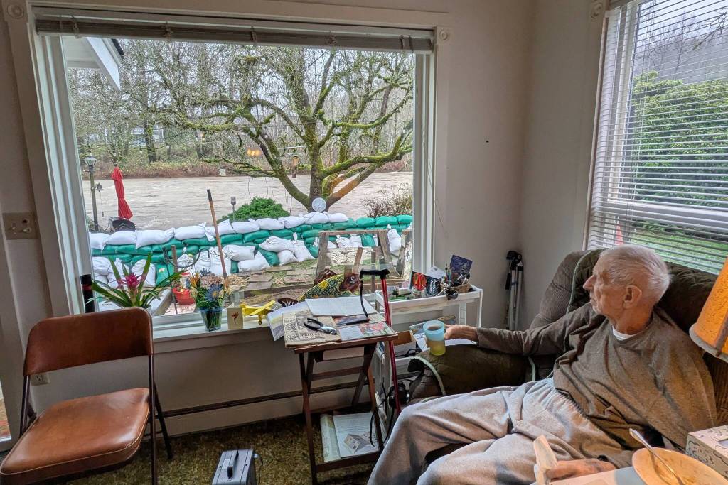 Jack Lyon, 94, sits in his chair and watches the Cedar River rush by only a meter from his window. Lyon, who has been living in his Maplewood Neighborhood home since the late 1950s, told the Renton Reporter that he's been able to gauge the water levels by how much he can see of his patio barbecue, which has not been swept away. Photo by Bailey Jo Josie/Sound Publishing
